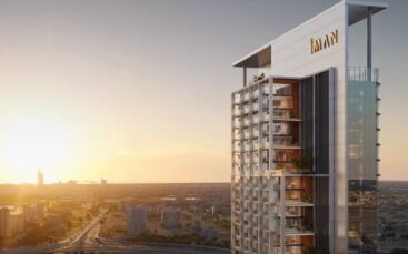 Une tour moderne avec des balcons en verre et des enseignes "IMAN" se dresse au coucher du soleil, surplombant un paysage urbain tentaculaire - c'est Sierra by IMAN, qui redéfinit l'habitat de luxe sur une ligne d'horizon urbaine époustouflante.