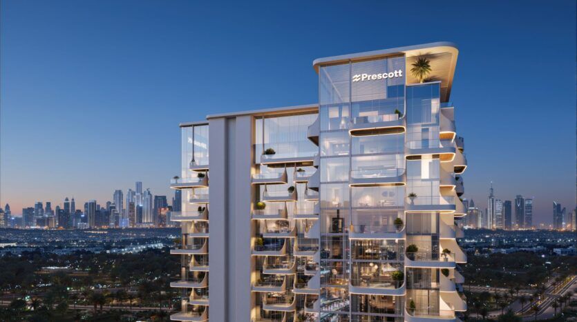 Un immeuble moderne de grande hauteur, The Caden, avec des balcons en verre, est montré au crépuscule, avec les lumières de la ville scintillantes et les gratte-ciel à l'arrière-plan. Le ciel clair et l'éclairage intense mettent en évidence la présence architecturale frappante de l'immeuble.