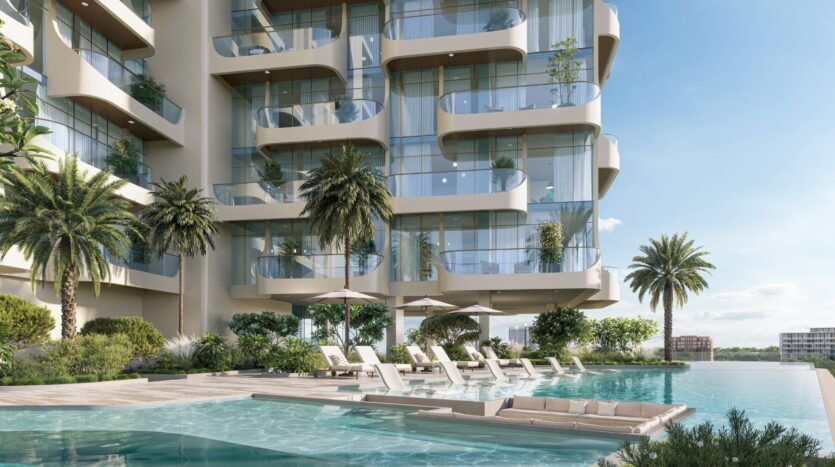 Le Caden est un immeuble d'appartements moderne doté de grands balcons en verre donnant sur une luxueuse piscine extérieure, des chaises longues et des parasols, le tout entouré de palmiers et d'une végétation luxuriante sous un ciel bleu limpide.