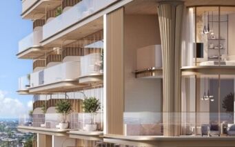 Le 113 Residences by Iman est un immeuble d'appartements de luxe moderne doté de vastes balcons en verre, de hautes fenêtres, d'un éclairage élégant et de plantes d'extérieur. Des tons neutres et chauds dominent la façade, avec des vues sur l'océan et la ville sous un ciel bleu limpide.