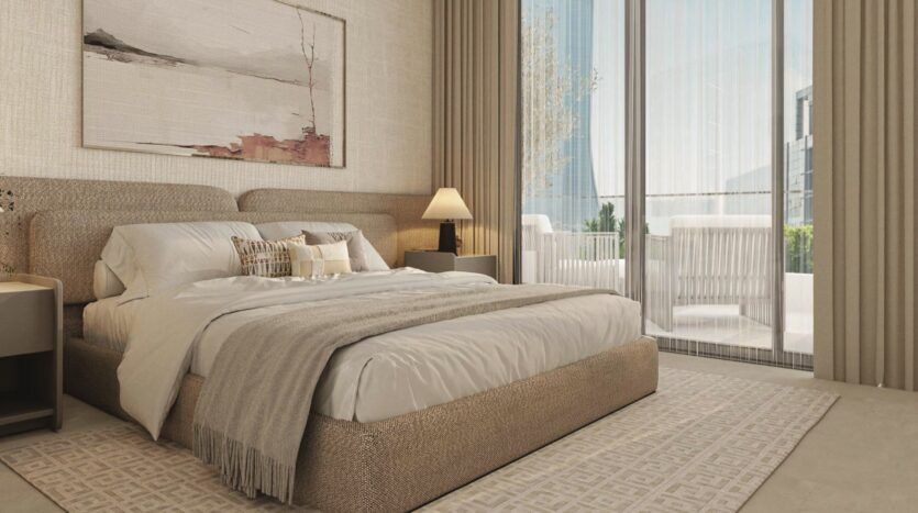 Chambre à coucher moderne à Vida Residences Saadiyat Island avec un grand lit, une literie neutre, des tables de chevet et des lampes, un tapis texturé, des œuvres d'art murales abstraites et des rideaux allant du sol au plafond encadrant des portes vitrées donnant sur un patio ensoleillé où l'on peut s'asseoir.