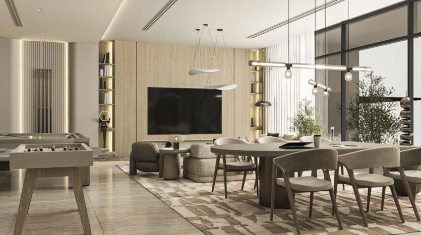 Le salon et la salle à manger modernes et ouverts de Vida Residences Saadiyat Island se caractérisent par des tons neutres, une grande télévision sur un mur lambrissé, un mobilier contemporain, un baby-foot et de grandes baies vitrées qui inondent l'espace de lumière naturelle.