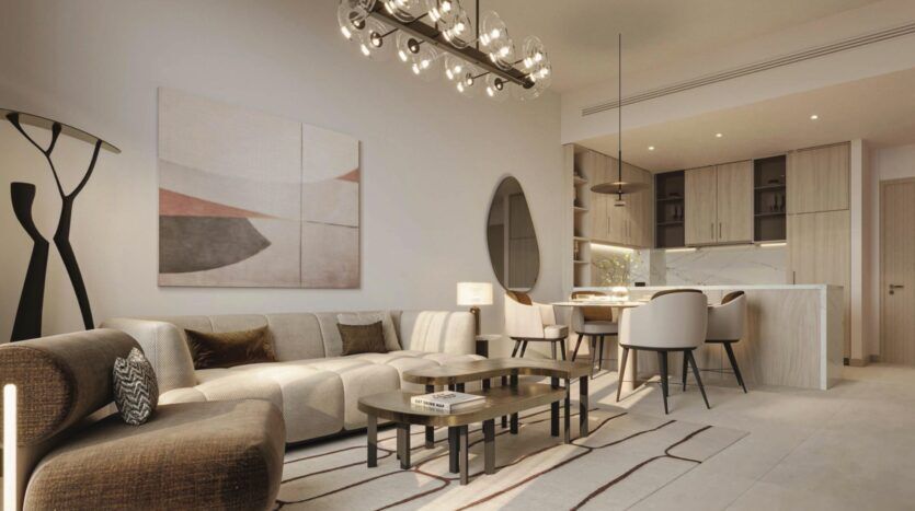 Un salon et une salle à manger modernes à Vida Residences Saadiyat Island avec des tons neutres, un canapé sectionnel, un art mural abstrait, une table à manger ronde et des chaises, un éclairage suspendu et une cuisine ouverte minimaliste à l'arrière-plan.