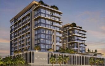 Immeuble moderne de plusieurs étages avec des façades vitrées, des balcons et un toit végétalisé, arborant le nom « Everly Place by Ellington » sur la façade ; entouré de palmiers au coucher du soleil.