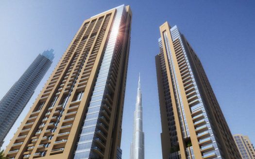 Une vue des gratte-ciels modernes de Dubaï, avec une très haute tour en arrière-plan sous un ciel bleu clair, la lumière du soleil éclairant l'un des bords du bâtiment.