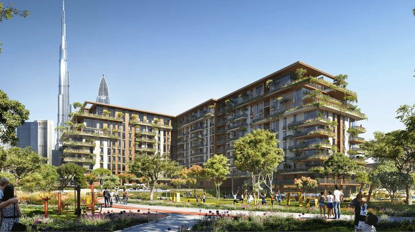Lush, green residential complex with modern multi-storey buildings, landscaped gardens reminiscent of a central park and people enjoying outdoor activities on a sunny day, with a tall skyscraper visible in the background.