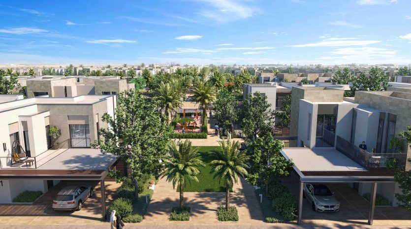 Vue aérienne d'Arabian Ranches 3, avec des rangées de maisons en duplex modernes, une végétation luxuriante, des palmiers et des voitures garées, centrées autour d'un jardin commun avec des coins salons.
