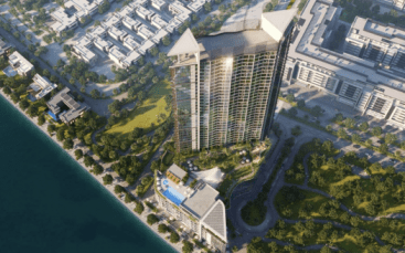 Vue aérienne d'un immeuble moderne de grande hauteur, Waves Grande, doté d'un toit unique en forme d'aile, entouré de parcs verts et situé à proximité d'un plan d'eau, avec d'autres bâtiments urbains dans le