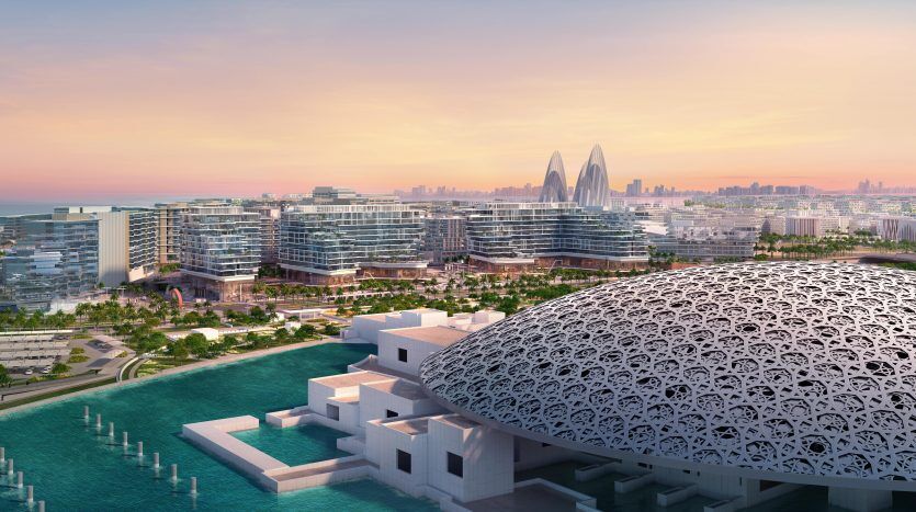 Vue aérienne d'un paysage urbain moderne au bord de l'eau au coucher du soleil à Dubaï, présentant une architecture distinctive comprenant un bâtiment en forme de dôme et des gratte-ciel futuristes en arrière-plan.