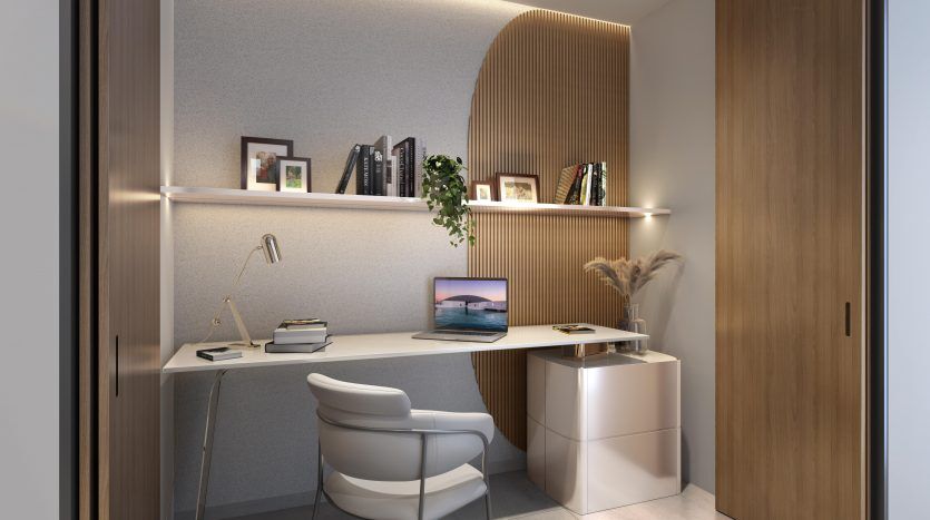Un coin bureau moderne dans une villa de Dubaï avec un bureau intégré, des étagères remplies de livres et de photos encadrées et un éclairage ambiant. Une chaise élégante et un ordinateur portable blanc élégant complètent l'espace.