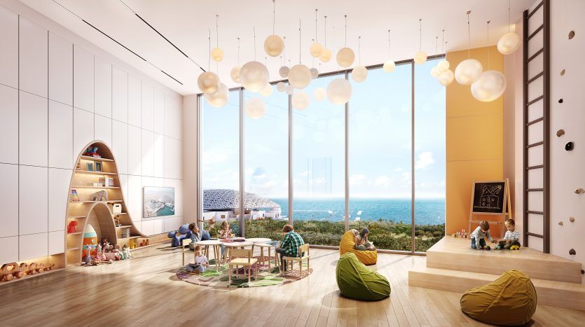 Villa spacieuse et ensoleillée à Dubaï avec de grandes fenêtres donnant sur la mer, meublée d'une aire de jeux, de poufs et d'une table à manger, où des personnes de différents âges se détendent et interagissent.