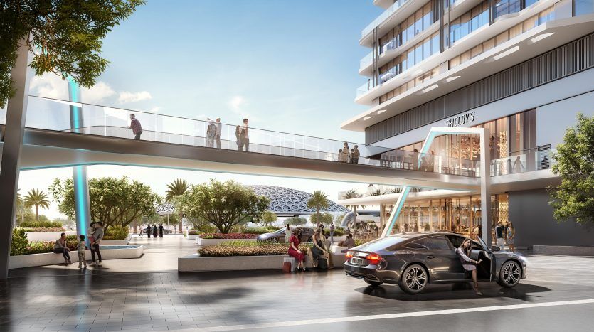 Une place extérieure animée à Dubaï avec des passants et une voiture qui passe, présentant une architecture moderne comprenant un pont reliant les bâtiments au-dessus de la rue, entouré de palmiers.