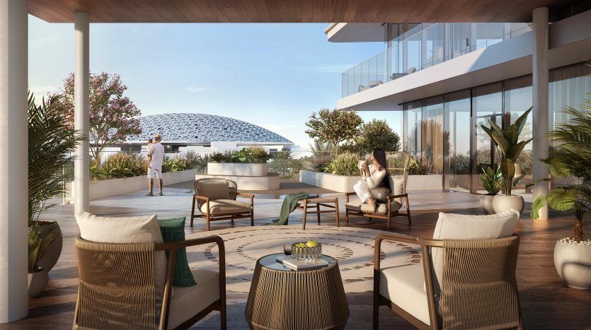 Un balcon moderne et spacieux doté de mobilier d'extérieur et de plantes décoratives. Deux personnes profitent de la vue sur une structure en forme de dôme unique au loin. Un éclairage chaleureux améliore l'ambiance sereine de cette villa à Dubaï.