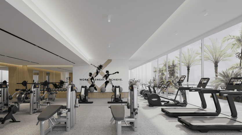 Une salle de sport spacieuse et moderne avec des tapis roulants, des vélos et des appareils de musculation, dotée de grandes fenêtres donnant sur la verdure et d'un texte de motivation disant « travailler, transpirer, réussir » sur le mur d'une villa de