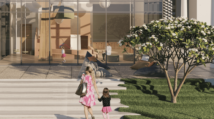 Une mère et sa fille se tenant la main passent devant une villa moderne à Dubaï dont les grandes fenêtres révèlent un intérieur spacieux et bien éclairé avec des personnages et des sculptures. La scène est ornée d’un arbre à fleurs luxuriantes.
