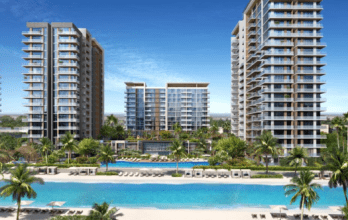 Une image représentant trois immeubles modernes de grande hauteur entourant un grand lagon artificiel avec des palmiers et des chaises de plage sous des parasols, représentant un cadre luxueux semblable à celui d'un complexe tropical à Dubaï.