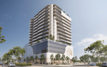 Immeuble moderne de grande hauteur avec balcons et espaces verts, avec une grande enseigne « Ocean Blue » sur la façade, sur fond de ciel bleu et flanqué d'arbres. Proposé par une agence immobilière leader à Dubaï.