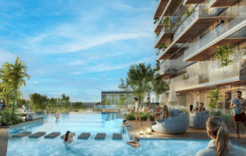 Les visiteurs se détendent et se baignent dans une piscine extérieure moderne entourée de verdure et d'un immeuble d'appartements de luxe avec balcons. Le ciel bleu et clair crée une atmosphère vibrante et accueillante.