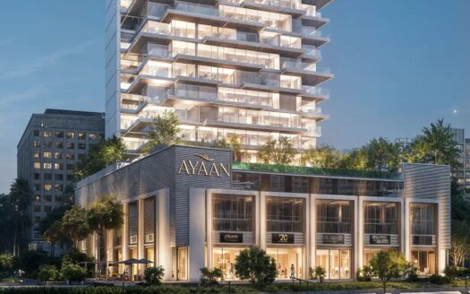 Ayaan Heights 1 by IGO est un immeuble moderne de plusieurs étages baptisé "Ayaan", qui propose des magasins aux étages inférieurs et une tour au-dessus avec des balcons et de la verdure, magnifiquement illuminée le soir.