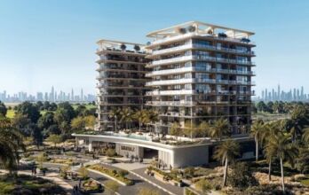 La résidence Inara est un immeuble résidentiel moderne de plusieurs étages avec de grands balcons, entouré de palmiers et de jardins paysagers. Une piscine étincelante se trouve à l'avant, avec une ligne d'horizon lointaine de la ville visible sous un ciel bleu clair.