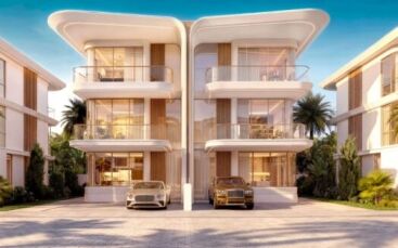 Deux villas de luxe modernes de trois étages à Greenz by Danube sont dotées de balcons incurvés et de grandes baies vitrées, chacune avec une voiture de luxe dans l'allée. Des palmiers et une végétation luxuriante entourent les bâtiments sous un ciel bleu limpide.