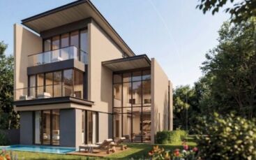 Maison moderne de trois étages à The Orchard by Sobha, avec de grandes baies vitrées et des balcons, entourée d'une végétation luxuriante et d'une pelouse bien entretenue, avec une petite piscine et des chaises longues dans l'arrière-cour par temps ensoleillé.
