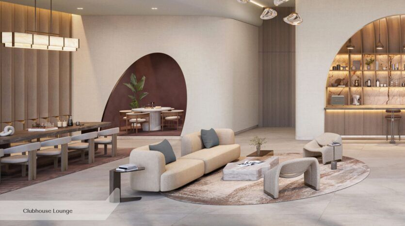 Le salon moderne du clubhouse d'Everly Place, conçu par Ellington, est agrémenté d'un canapé et de fauteuils beiges aux lignes courbes, disposés sur un tapis circulaire, à côté d'une longue table à manger. Au fond, des ouvertures en arc dévoilent un coin repas et un bar doté d'étagères et d'un éclairage décoratif.