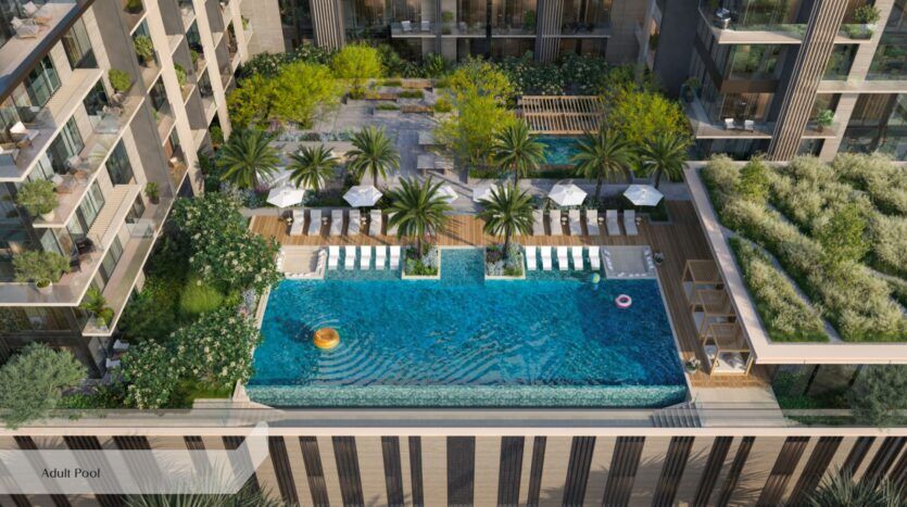 La piscine à débordement située sur le toit de l'Everly Place by Ellington est entourée de chaises longues, de palmiers et de coins salon ombragés, avec en toile de fond des immeubles d'appartements modernes et un aménagement paysager luxuriant. On aperçoit des bouées dans l'eau.