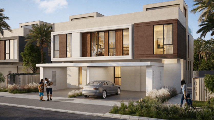 Maison moderne à deux étages avec toits plats et grandes fenêtres située dans les collines de Dubaï, entourée de palmiers. Une famille discute à côté d’une voiture garée et une femme passe devant le portail d’entrée.