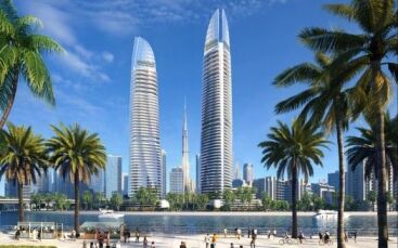 Un paysage urbain animé avec deux grands gratte-ciel en verre par une journée ensoleillée, avec des palmiers au premier plan et des gens profitant d'activités au bord d'une promenade au bord de l'eau à Dubaï.