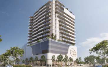 Rendu artistique d'un immeuble résidentiel moderne à plusieurs étages avec balcons, grand espace commercial au rez-de-chaussée et piétons. Une verdure luxuriante entoure le bâtiment sous un ciel bleu clair, idéal pour investir