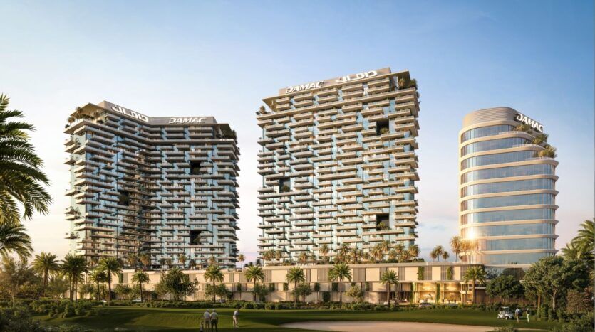 Trois tours modernes avec balcons et verdure, situées dans le Damac District Dubai, s'élèvent au-dessus de palmiers et d'un terrain de golf sous un ciel dégagé. Les bâtiments sont surmontés d'une enseigne "DAMAC" bien visible.