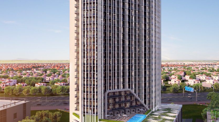 Un grand bâtiment moderne de grande hauteur avec des lignes verticales élégantes et une structure basse intégrée présentant des motifs bayz complexes. Les environs comprennent des maisons à toit plat et de la verdure sous un ciel dégagé