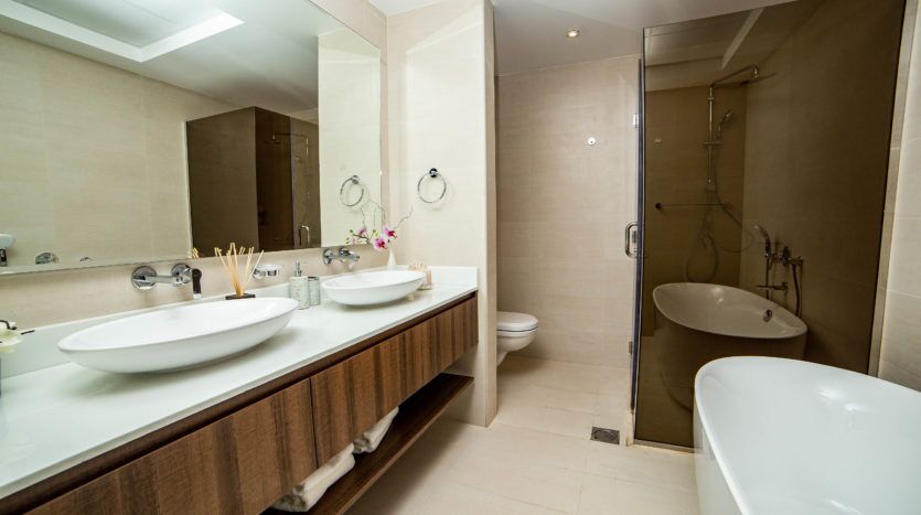 Intérieur de salle de bains moderne avec deux lavabos, de grands miroirs, une baignoire autoportante, un espace douche séparé et une décoration en carrelage neutre inspirée de Q Gardens Dubai.