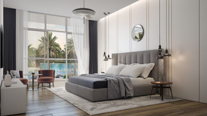 Une chambre moderne dans un appartement de Dubaï comprenant un grand lit avec une tête de lit et une literie grises, du parquet, des murs blancs et une vue sur un paysage de palmiers à travers une baie vitrée