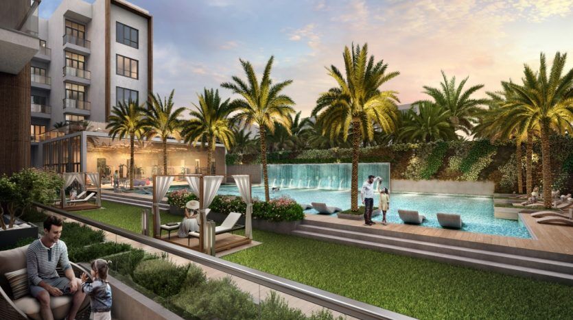 Un quartier résidentiel luxueux avec des palmiers et une grande piscine au coucher du soleil. Les gens se détendent et socialisent dans différents coins salons. Une famille avec un chien est assise au premier plan du Panthéon Ely