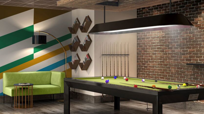Une salle de jeux élégante avec une table de billard, des motifs muraux géométriques colorés, des briques apparentes et un espace mini-golf. Un canapé vert et des étagères en bois sur Imperial Avenue ajoutent à l'ambiance moderne.