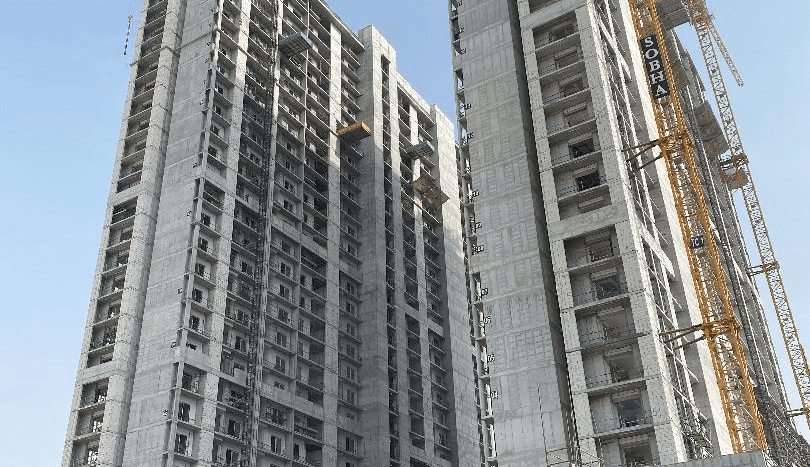 Photo d'un grand bâtiment en construction avec plusieurs grues et échafaudages contre un ciel clair à Creek Vistas, Dubaï.