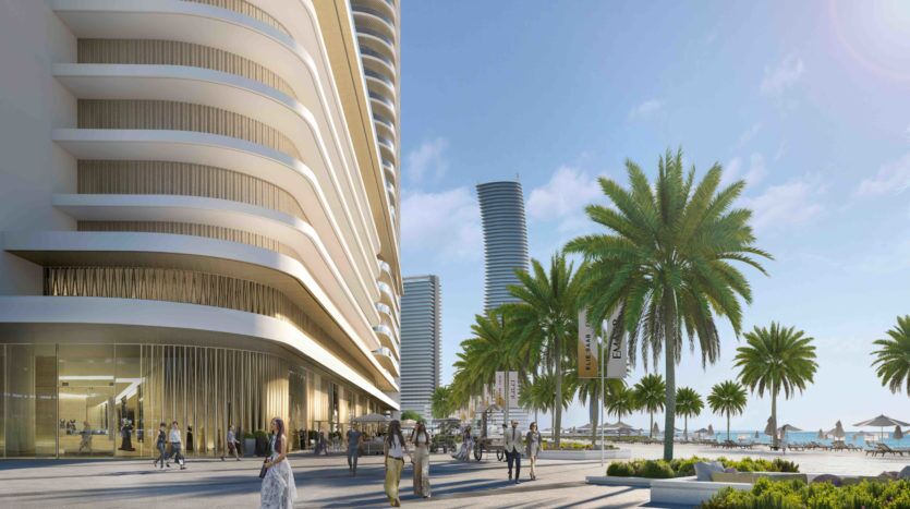 Un immeuble de grande hauteur moderne et curviligne à côté d'une promenade bordée de palmiers remplie de piétons sous un ciel bleu clair sur le front de mer d'Elie Saab Emaar.