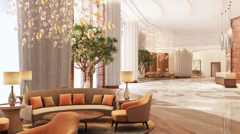 Un hall d'entrée luxueux sur Imperial Avenue, doté d'élégants sols en marbre, de sièges orange moelleux, de grandes colonnes décoratives gainées de lumières scintillantes et d'arbres verts luxuriants. Un éclairage tamisé et chaleureux met en valeur le style sophistiqué