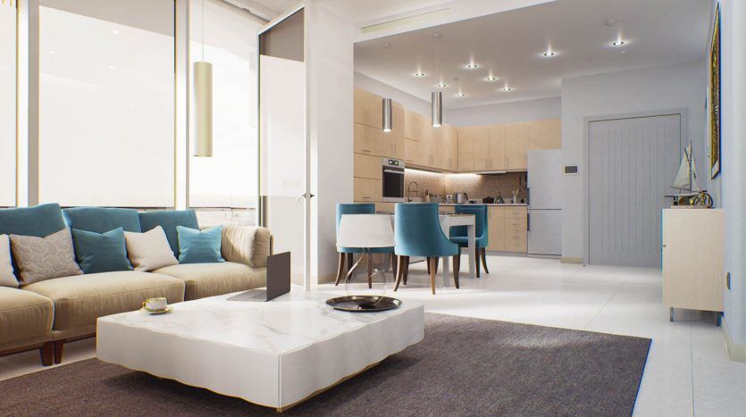 Espace de vie moderne et ouvert avec vue sur le golf, combinant une cuisine avec des armoires blanches, un coin repas avec une table ronde et des chaises bleues et un salon avec un canapé beige et des coussins turquoise.