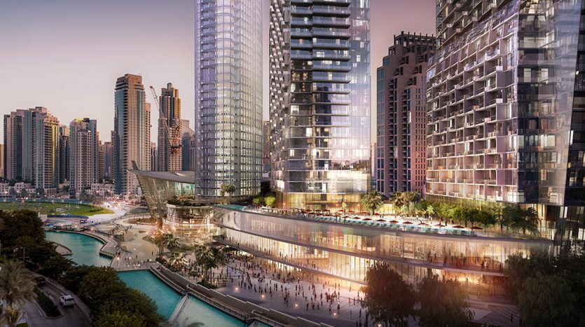 Une scène urbaine animée au bord de l'eau au crépuscule, avec des gratte-ciel modernes, dont l'Address Residences Dubai Opera, une promenade avec des piétons et un canal éclairé par des lumières de rue et de bâtiment.