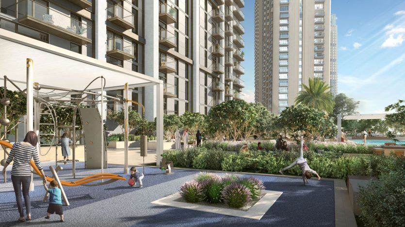 Une scène de terrain de jeu dynamique dans un parc urbain avec des enfants qui jouent et des adultes qui les surveillent au milieu d'une verdure luxuriante et des bâtiments de Burj Crown en arrière-plan.