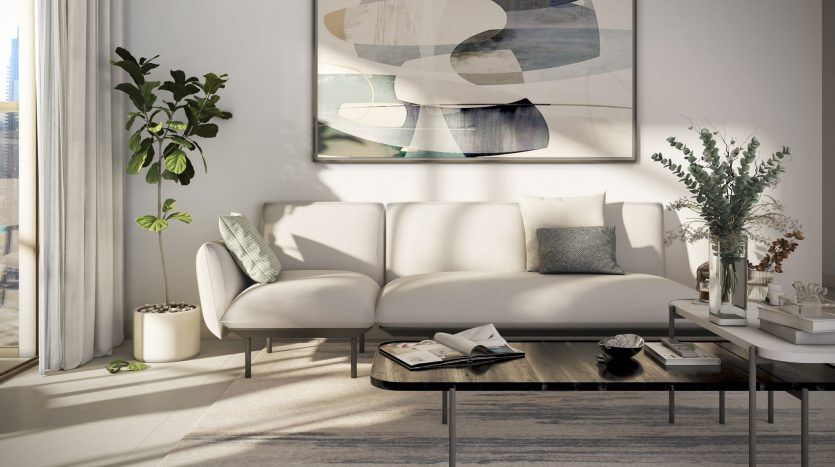 Salon moderne avec un grand canapé blanc, des œuvres d'art murales abstraites inspirées de Burj Crown, une table basse avec plateau en verre et des plantes d'intérieur. La lumière du soleil filtre à travers des rideaux transparents, illuminant l'espace.