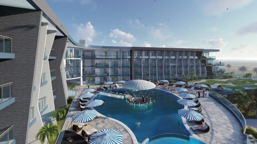 Complexe luxueux avec une grande piscine extérieure, entourée de chaises longues sous des parasols à motifs, vue sur la plage et bâtiments architecturaux modernes sur Samanag Golf Avenue par une journée ensoleillée.