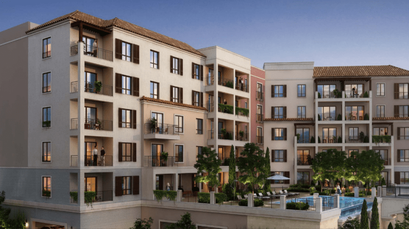 Un rendu numérique du luxueux complexe d'appartements "La Voile Port de la Mer" au crépuscule, avec des balcons, des toits de tuiles et une verdure luxuriante, positionné à côté d'un plan d'eau serein.