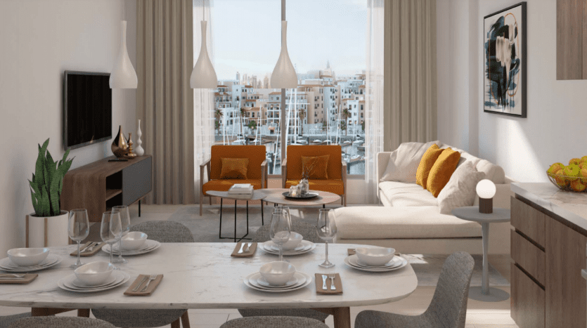 Salle à manger et salon moderne et bien éclairé avec une table en marbre pour quatre personnes, adjacent à un espace avec un canapé beige et des fauteuils orange, donnant sur La Voile Port de la Mer à travers