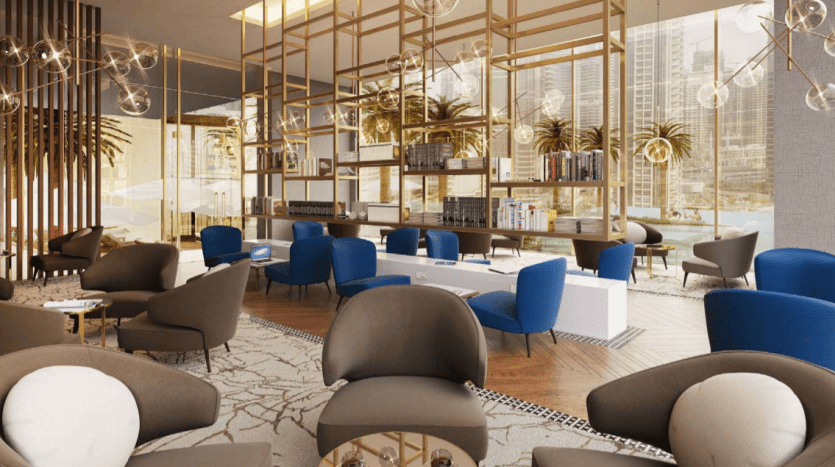 Salon luxueux et moderne du Jumeirah Living Marina Gate avec divers coins salons, dotés de chaises et de canapés moelleux, décorés d'accents et d'étagères dorés. De grandes fenêtres offrent une vue sur les gratte-ciel.