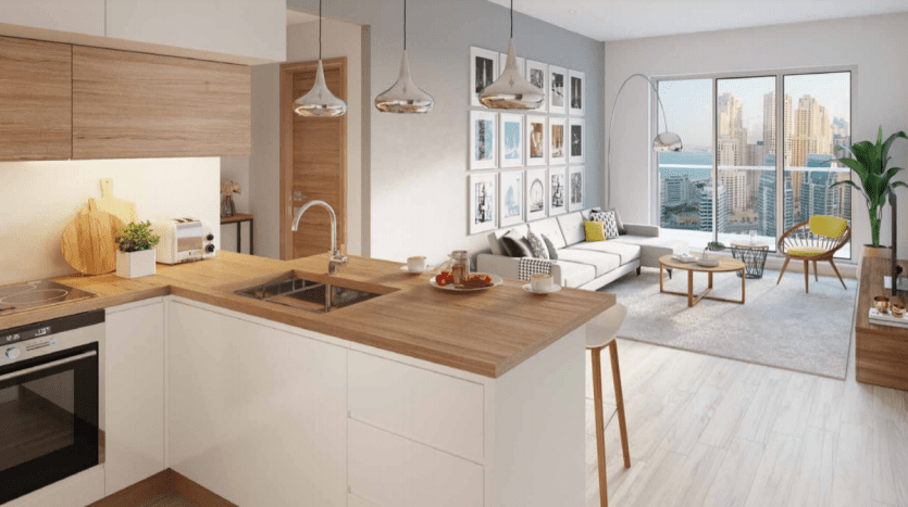 Intérieur d'un studio moderne et décloisonné dans la marina de Dubaï avec une cuisine dotée d'une finition en bois, d'appareils intégrés et d'un bar pour le petit-déjeuner, menant à un salon avec canapé, chaises et vue sur le paysage urbain à travers un grand