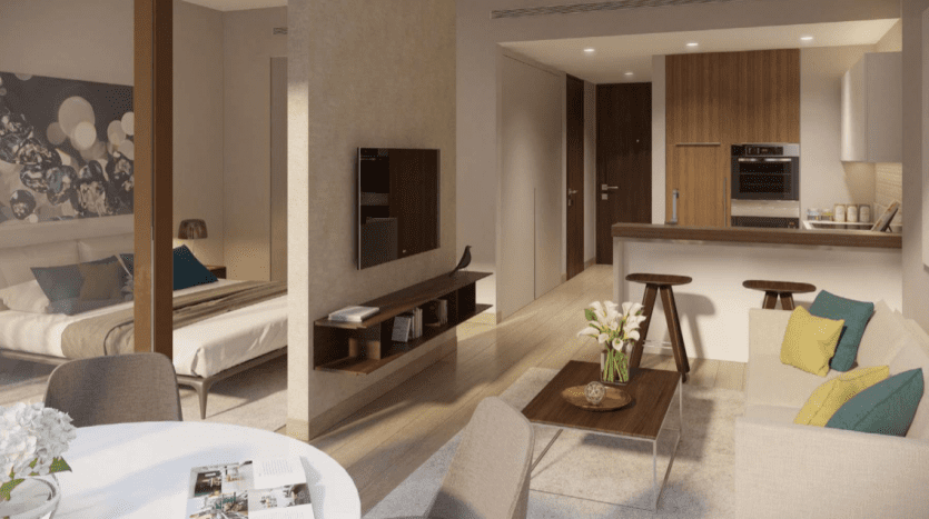 Intérieur d'appartement moderne à Jumeirah Living Marina Gate présentant un plan ouvert avec un salon doté d'un canapé et d'une table basse, et une cuisine adjacente avec armoires intégrées. Le décor comprend des œuvres d'art florales